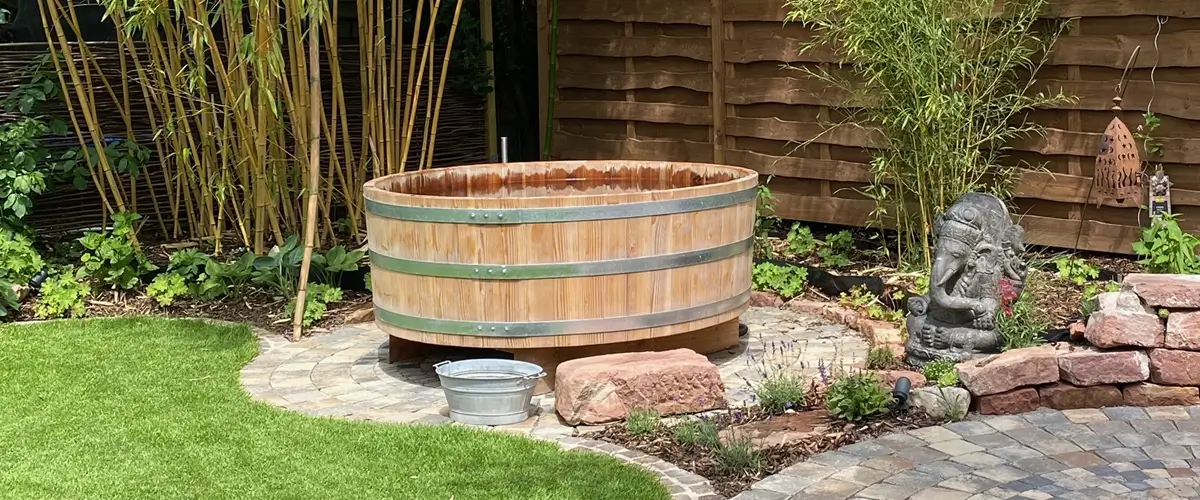 Badebottich Ein hölzerner Bottich in einem Zengarten gefüllt mit Wasser zum Baden.
