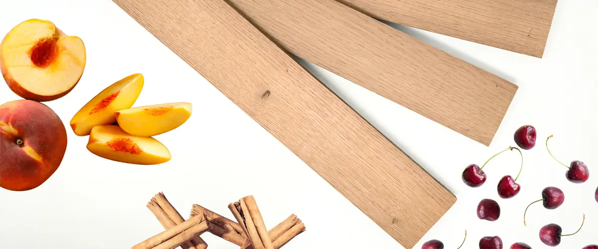 Holz Staves und Sticks Im Anschnitt sind drei Holzbretter, sogenannte Staves zu sehen. Drum herum sind Pfirsiche, Kirschen und Zimt, um den zu erwartenden Geschmack der Staves darzustellen.